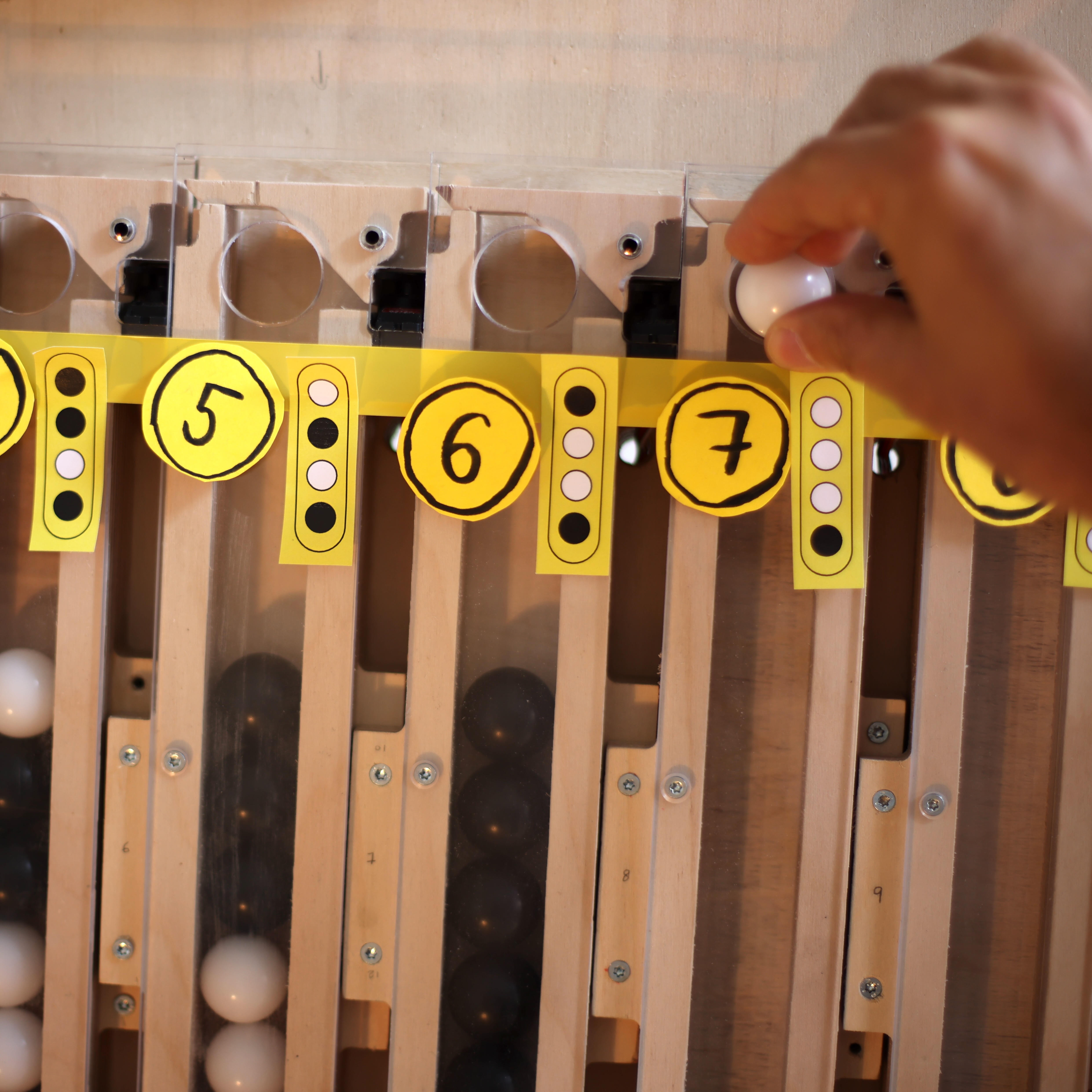 Une main dépose dans un tube une bille représentant un bit d'une instruction